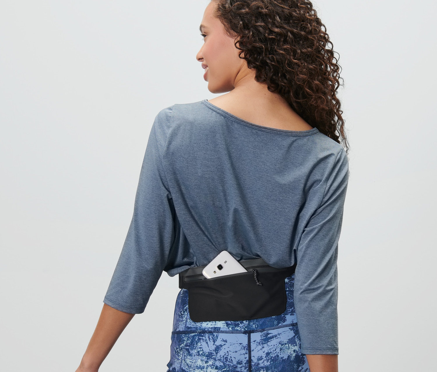 Femme portant une ceinture de course noire pour smartphone.