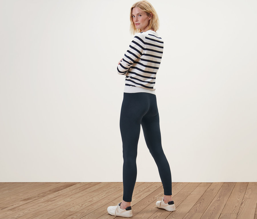 Femme posant en legging et pull rayé.
