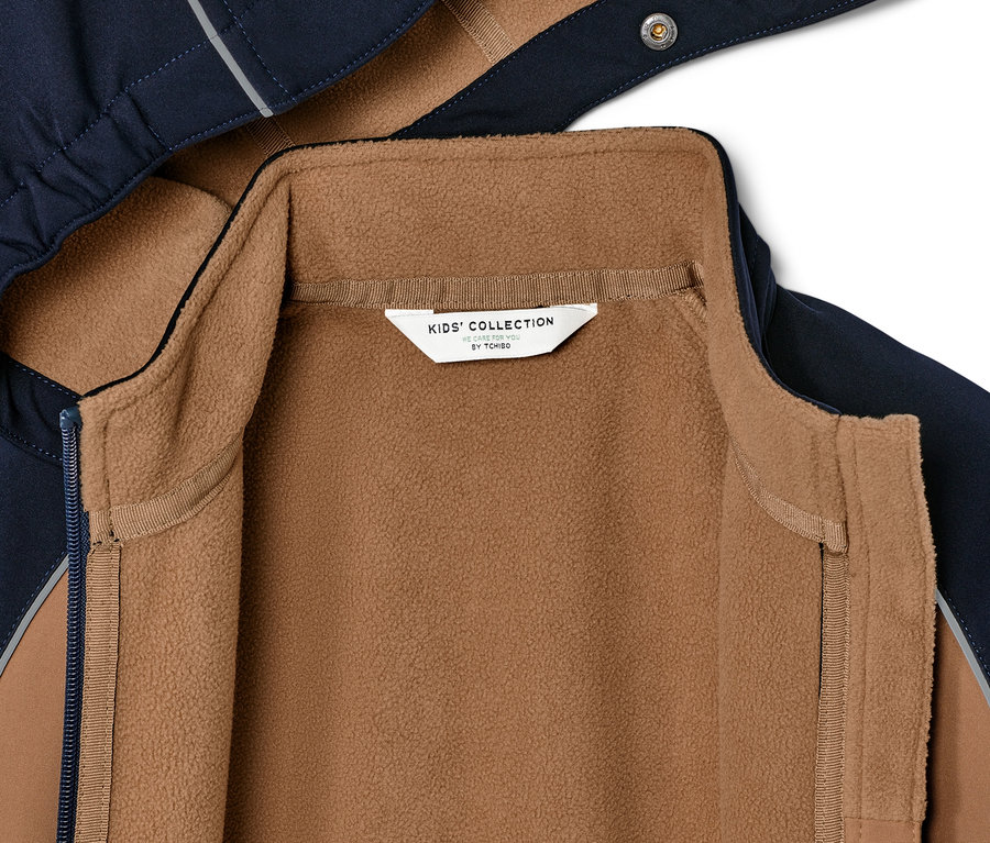 Gros plan sur une veste en softshell pour enfant avec une doublure polaire marron.