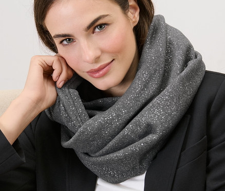 Une femme est assise avec une écharpe-tube scintillante autour du cou.
