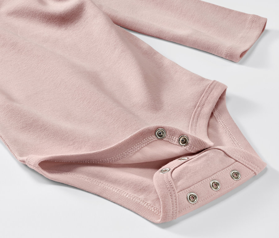 Gros plan sur un body rose à manches longues pour bébé, faisant partie d'un ensemble de 5.