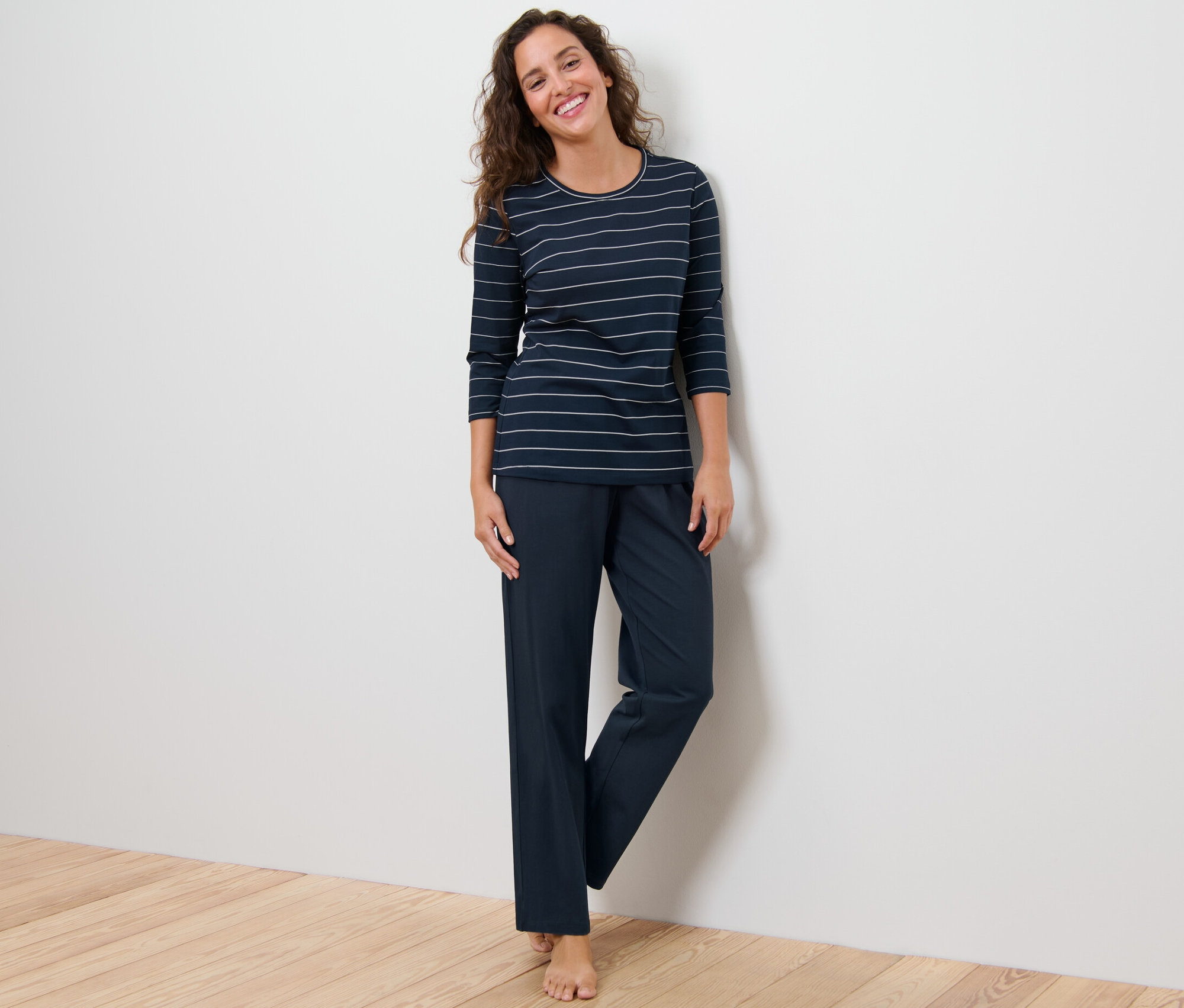 Une femme debout porte un pyjama à rayures.