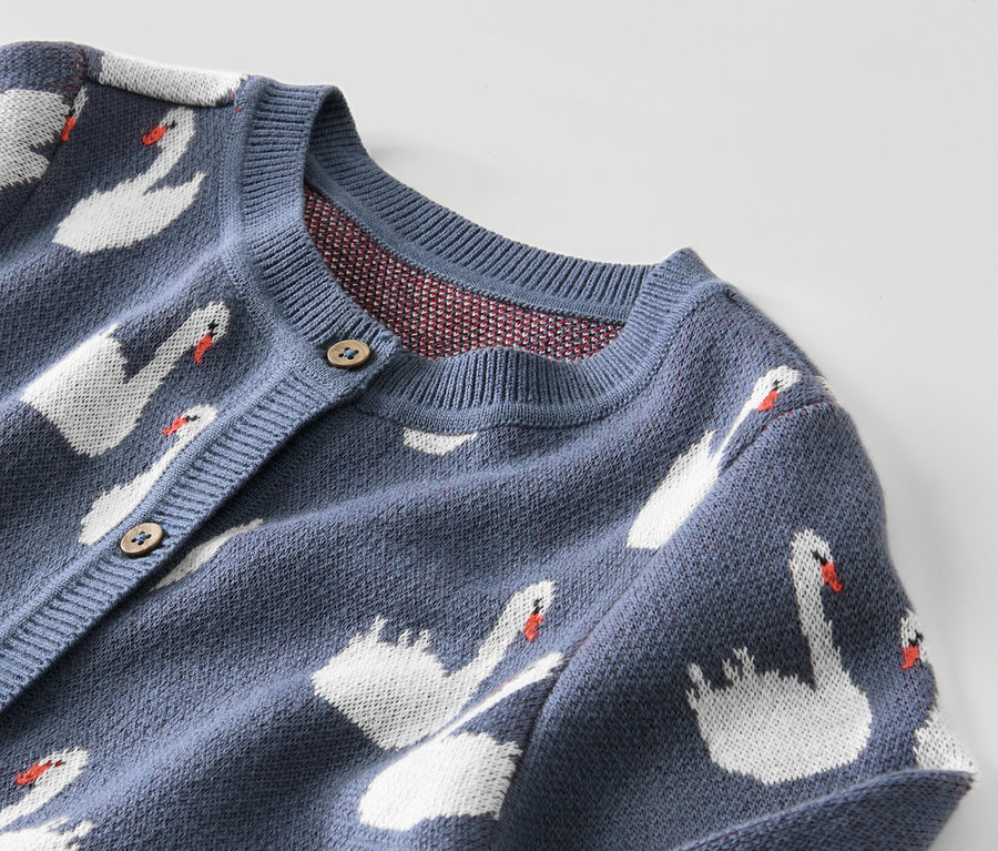 Gros plan sur un gilet en maille bleu pour enfant avec des motifs de cygnes.