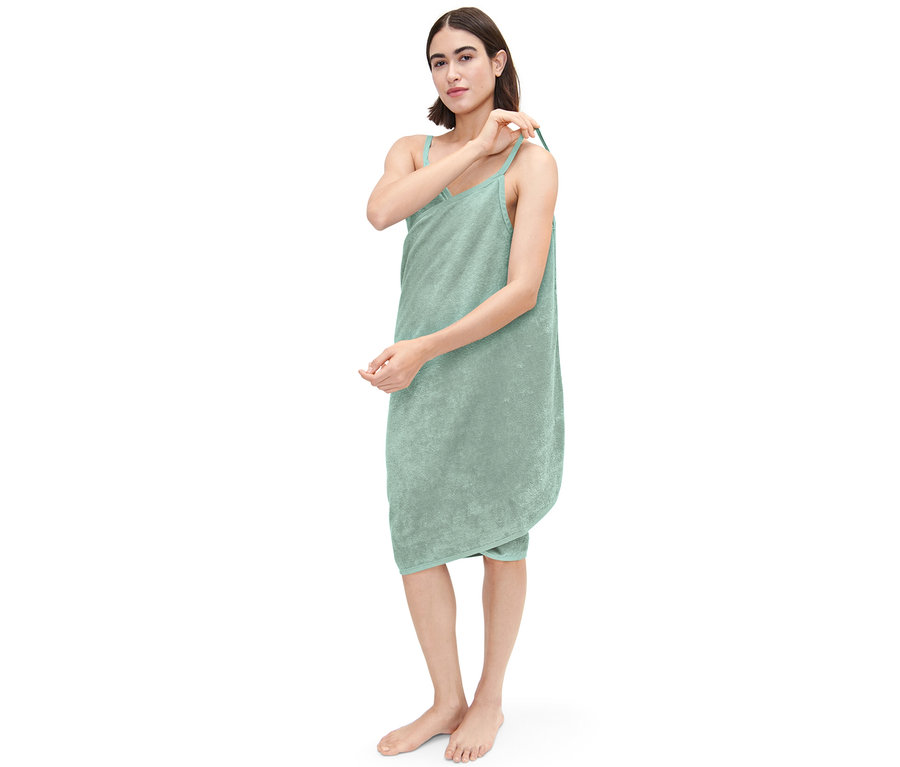 Femme ajustant la bretelle d'une robe de chambre verte.