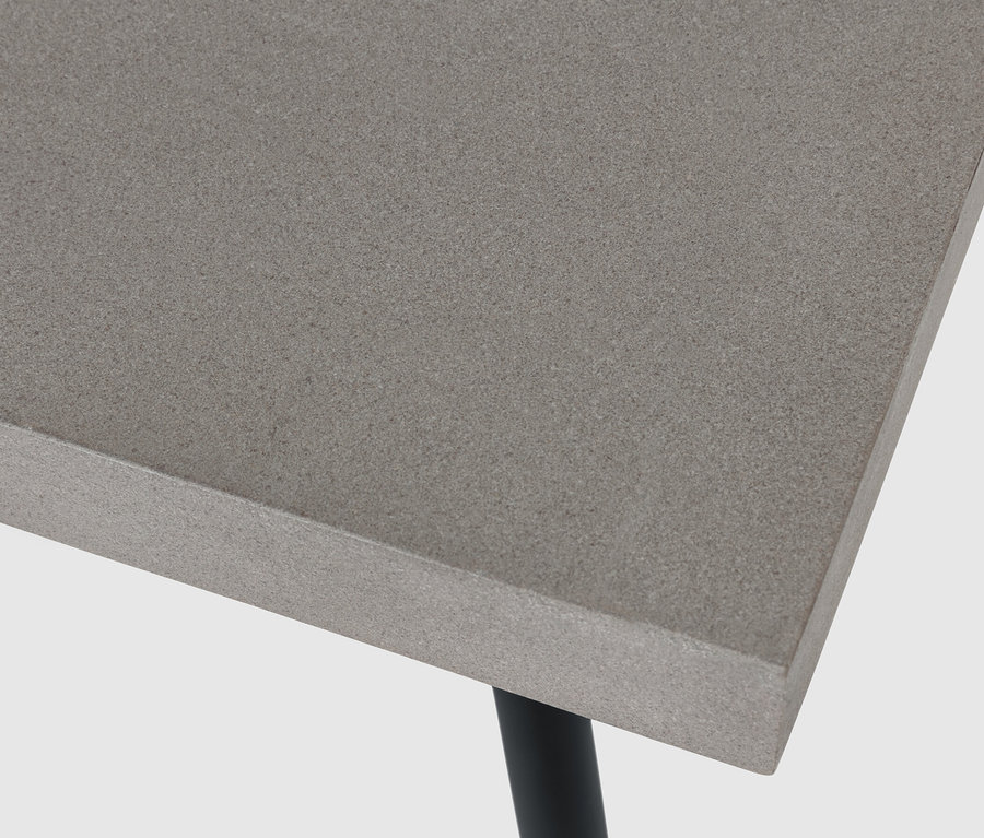 Vue détaillée d'une table basse avec plateau en polyciment et pieds noirs.