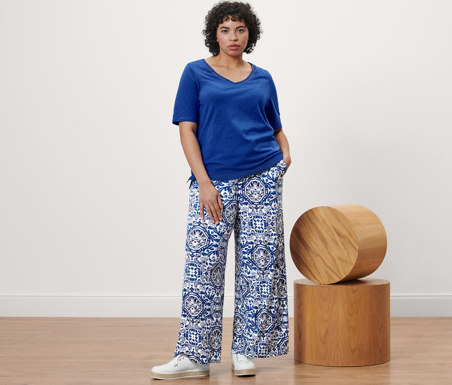 Femme posant dans un haut bleu cobalt et un pantalon palazzo imprimé.