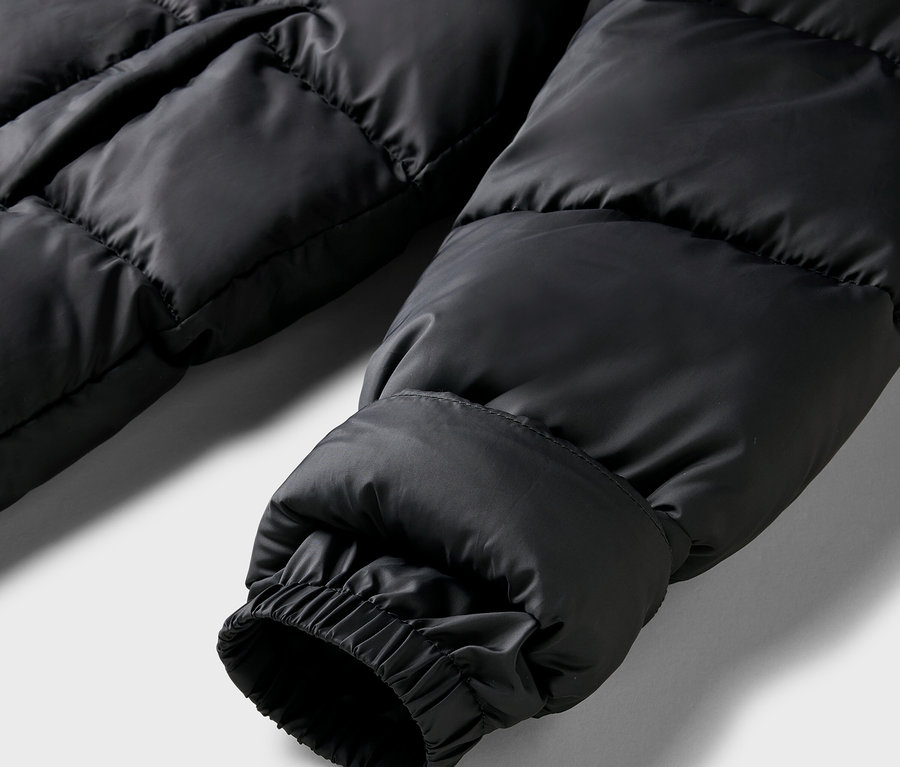 Gros plan sur la manche d'un manteau matelassé noir avec poignet élastique.