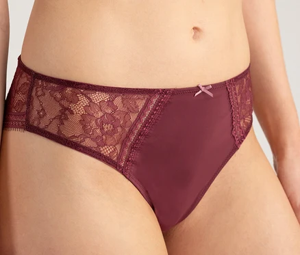 Torse d'une personne portant un slip taille haute Passionata « Jeanne » bordeaux avec des empiècements en dentelle sur les côtés et un petit nœud.