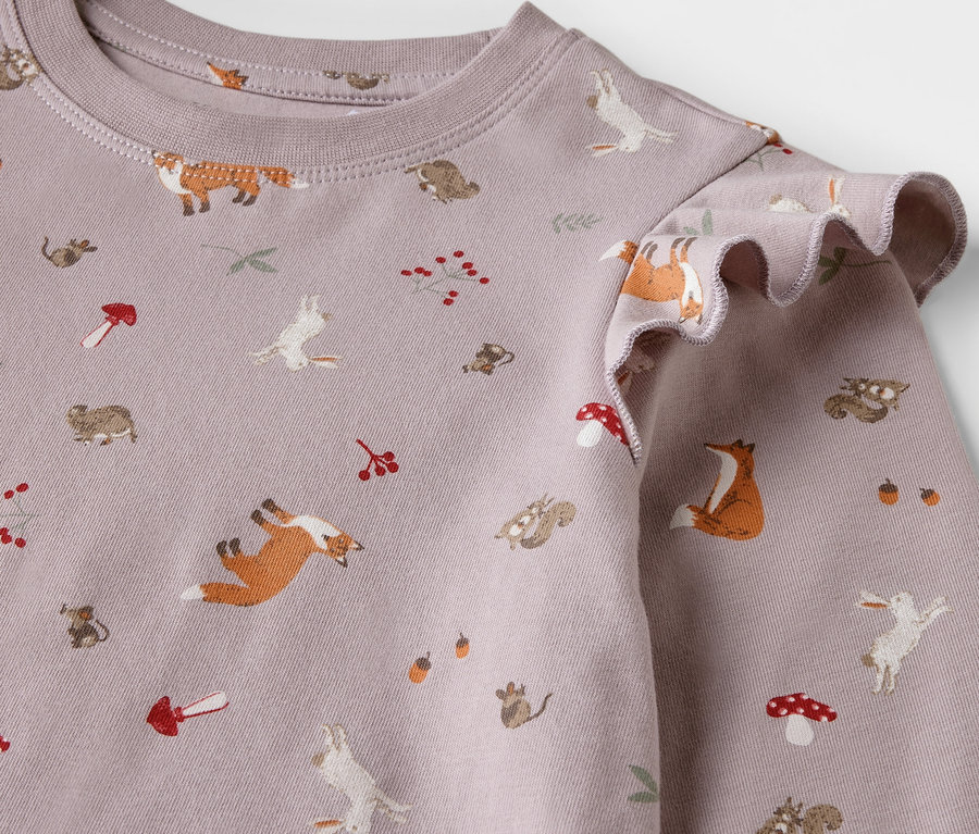 Gros plan sur une chemise de nuit pour enfant avec un imprimé de renards, de lapins, d'écureuils et de champignons.
