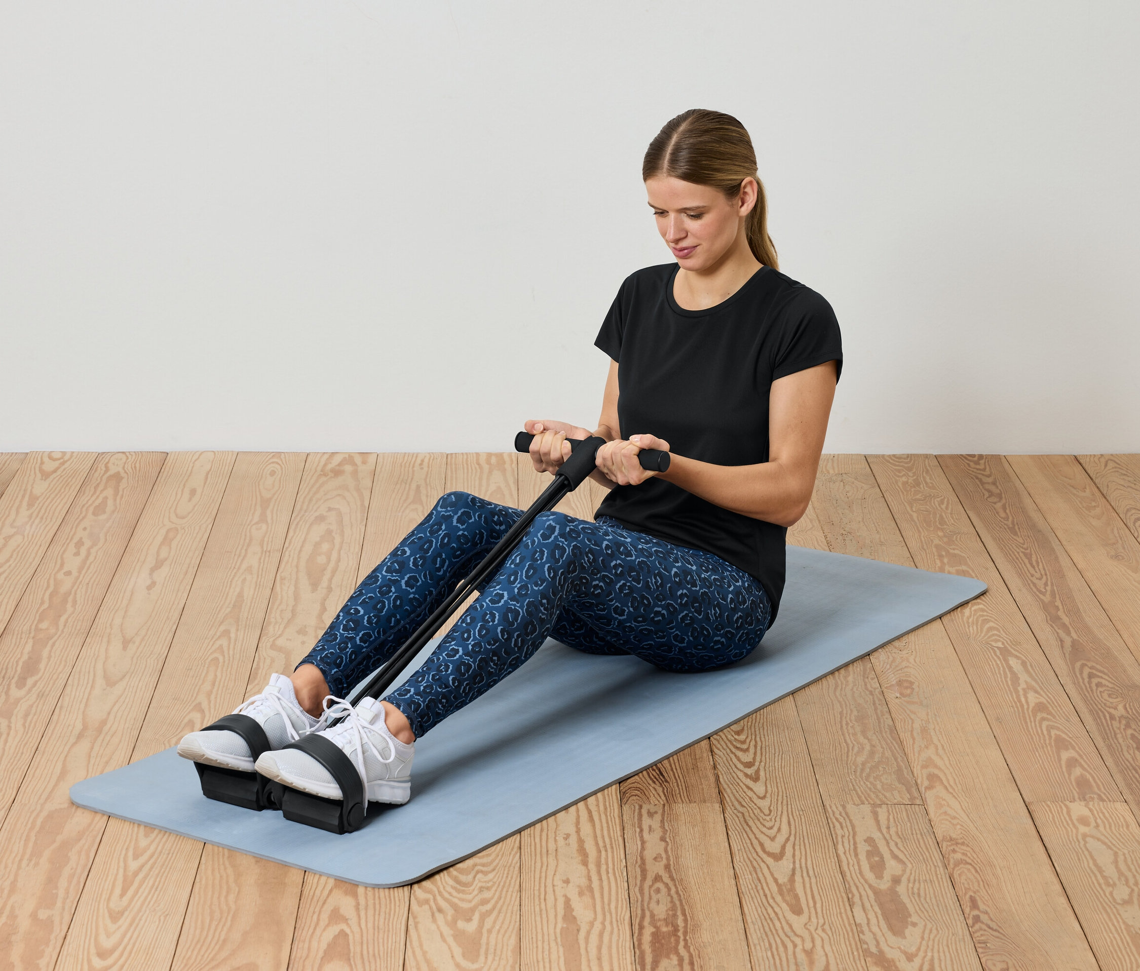 Femme faisant de l'exercice avec un expandeur sur un tapis.