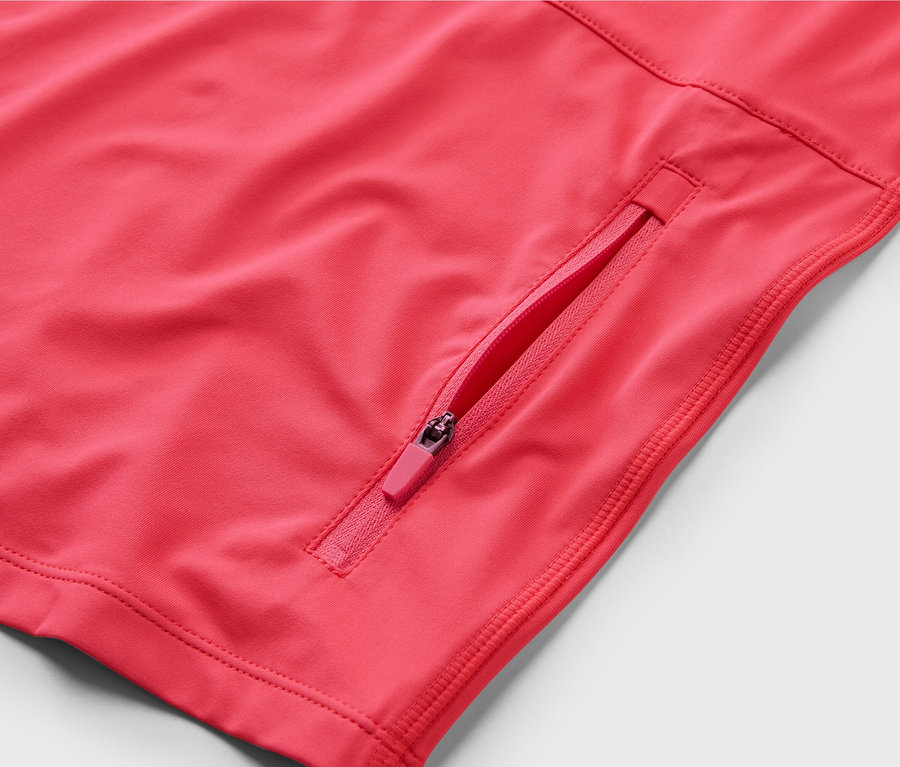 Gros plan sur un t-shirt de cyclisme rose à manches courtes avec une poche zippée.