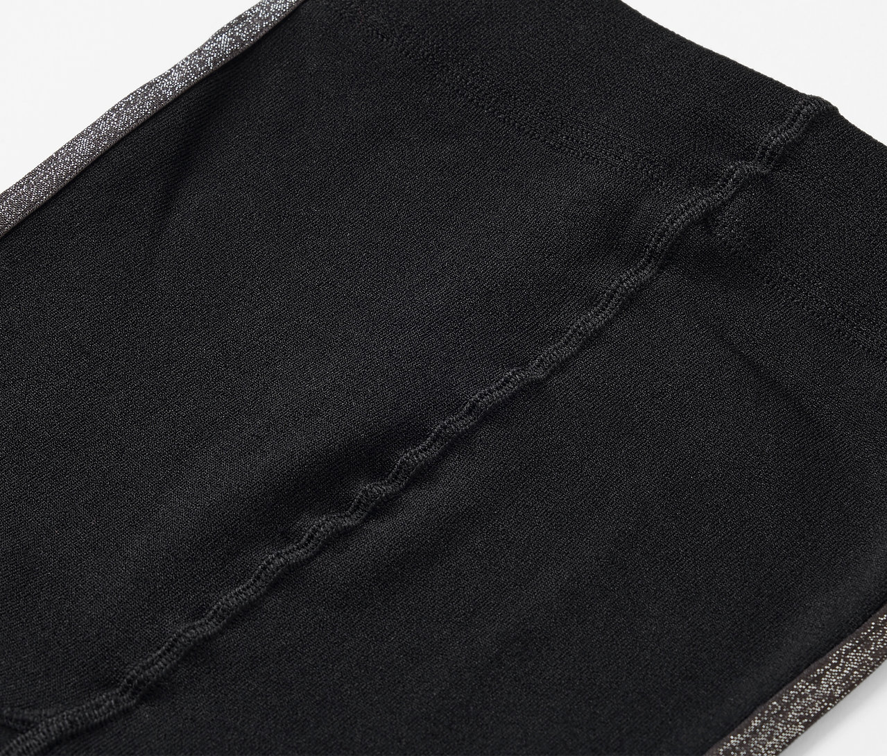 Gros plan sur un legging noir avec une bande latérale grise.