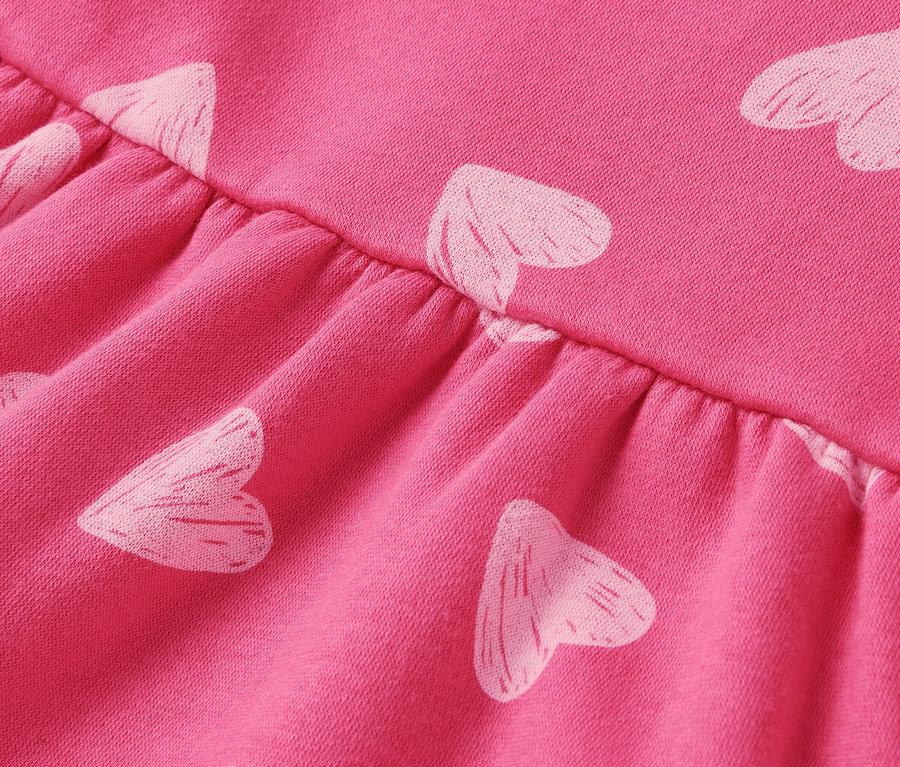 Gros plan d'un tissu rose avec des cœurs blancs et des fronces.