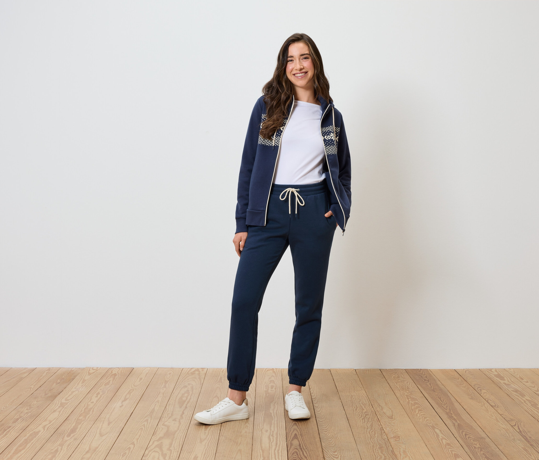 Une femme pose dans un survêtement bleu marine et un t-shirt blanc.