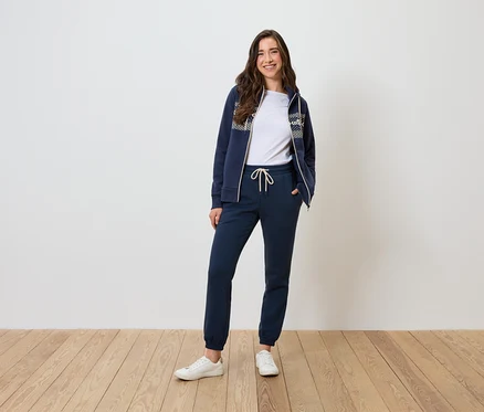 Une femme pose dans un survêtement bleu marine et un t-shirt blanc.