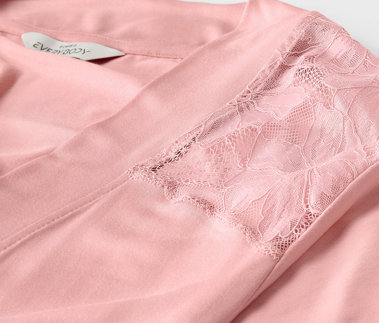 Détail d'une robe de chambre rose avec de la dentelle sur la manche.