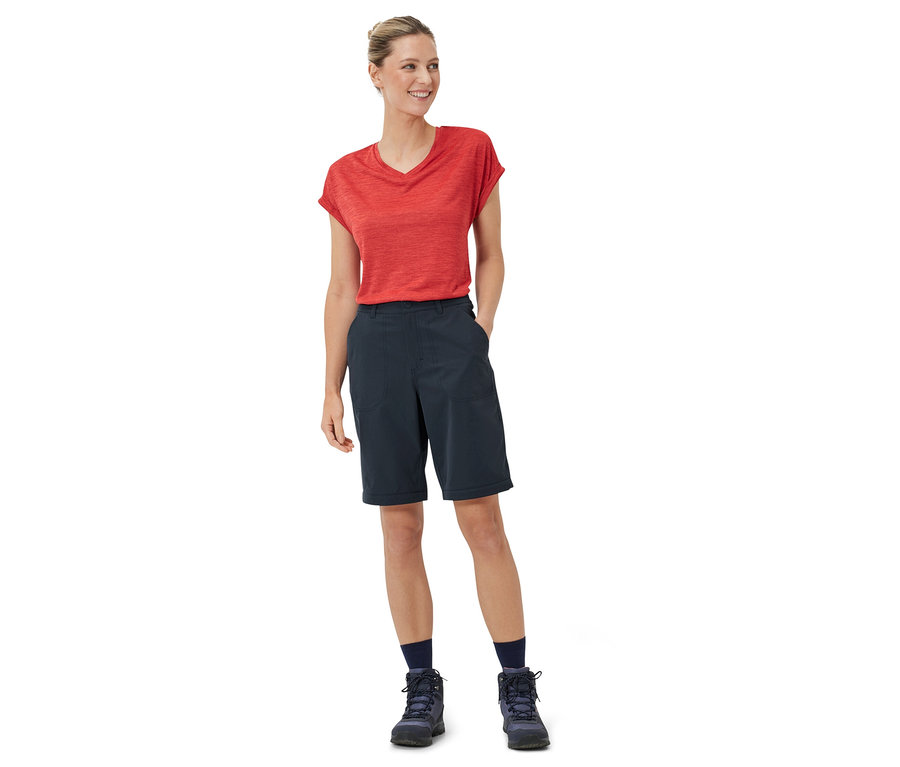 Une femme debout portant un t-shirt rouge et un pantalon fonctionnel 2 en 1 bleu.