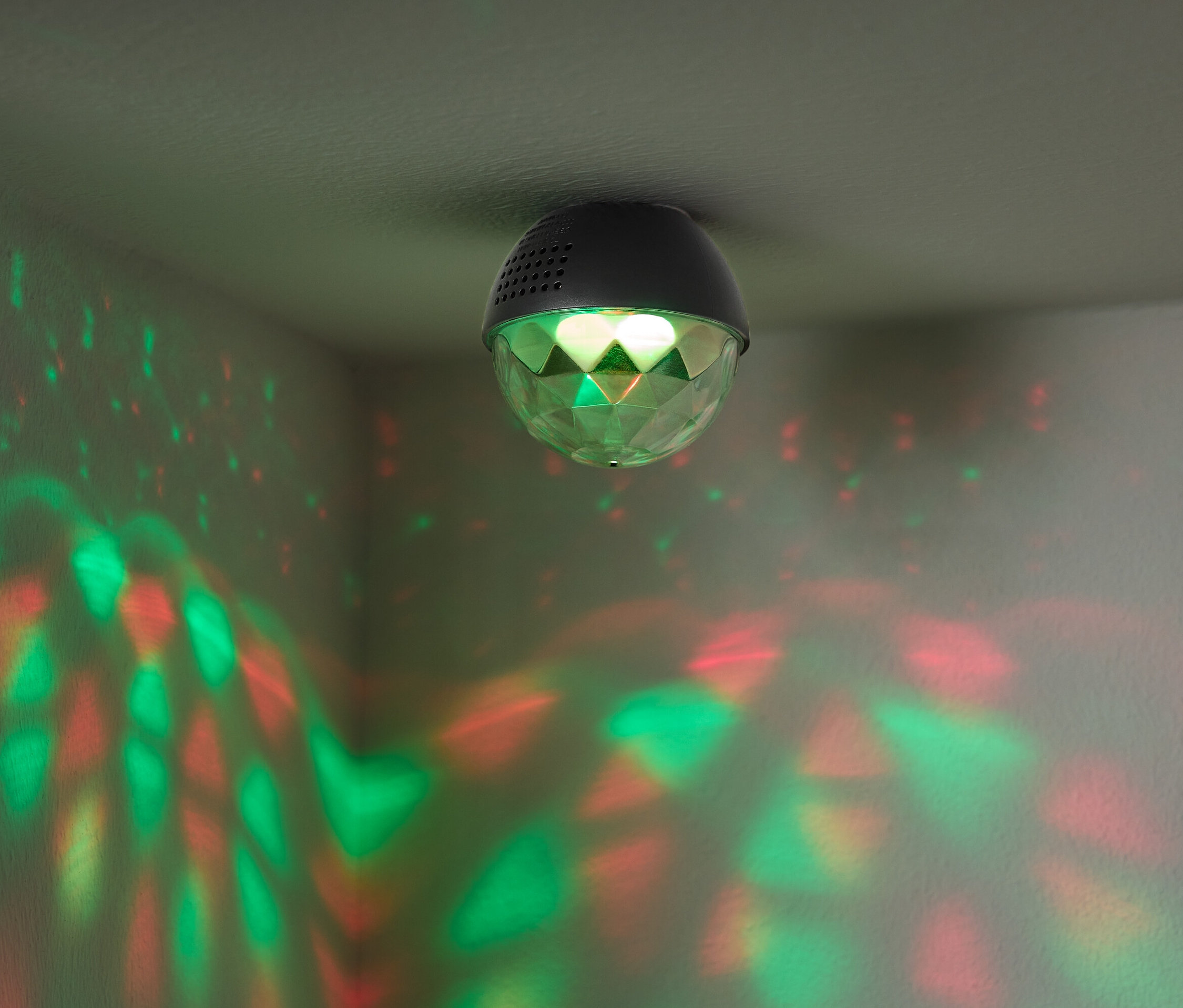 Une boule disco fixée au plafond projette des lumières rouges et vertes sur les murs.