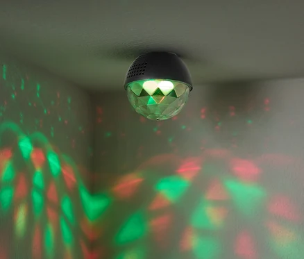 Une boule disco fixée au plafond projette des lumières rouges et vertes sur les murs.