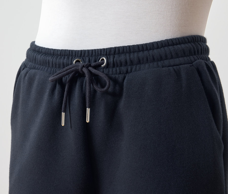 Détail d'un pantalon de survêtement bleu foncé avec cordon de serrage à la taille.