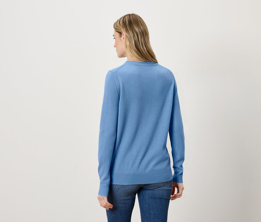 Vue arrière d'une femme blonde portant un pull bleu et un jean.