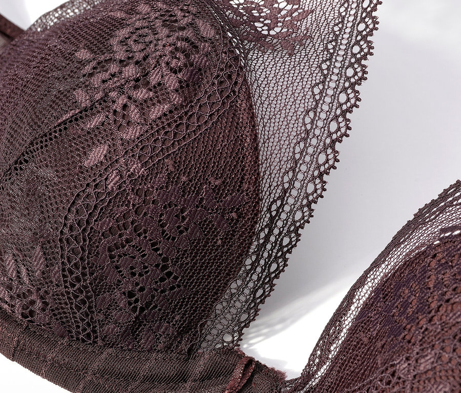 Gros plan d'un soutien-gorge en dentelle violet foncé sur fond blanc.