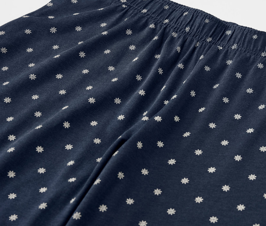 Gros plan d'un pantalon bleu marine avec des fleurs blanches et une taille élastique.