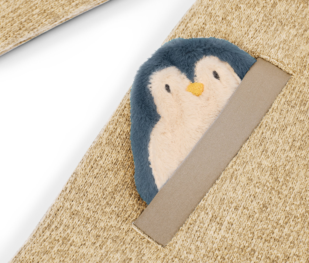 Détail d'un tapis beige avec un pingouin en peluche cousu.