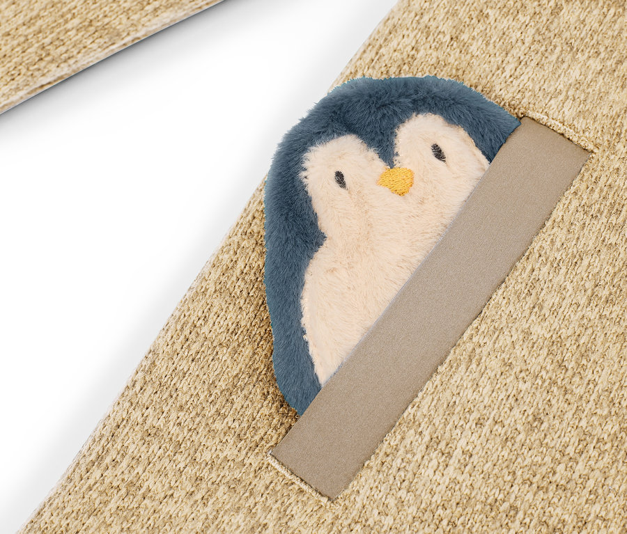 Détail d'un tapis beige avec un pingouin en peluche cousu.