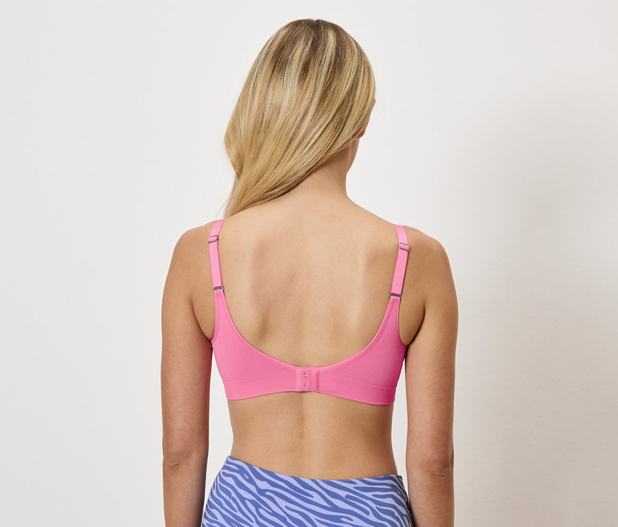 Vue de dos d'une femme aux cheveux blonds portant un soutien-gorge rose et un legging bleu à motif animal.
