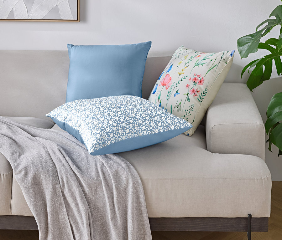 Sur un canapé sont disposés trois coussins et une couverture.