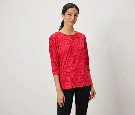 Une femme porte un haut rouge à motif animalier et un legging noir.