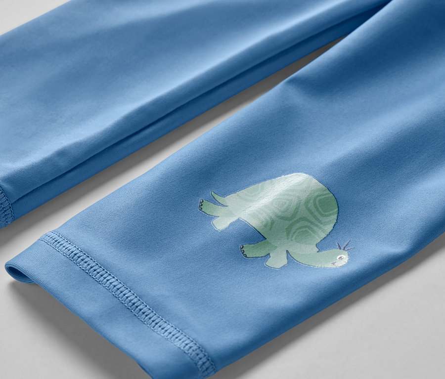 Gros plan sur un legging de bain pour enfant avec protection UV 80, orné d'un motif de tortue.