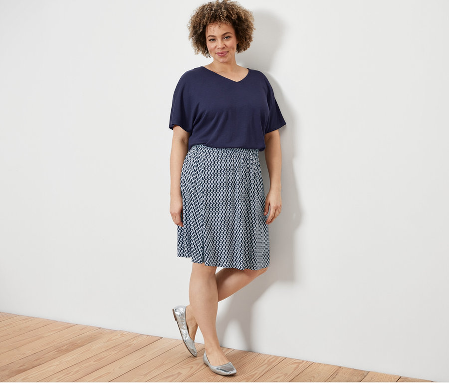 Femme posant dans une blouse structurée bleu foncé et une robe en jersey imprimée.