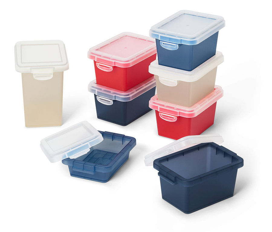 Des récipients de stockage multicolores avec des couvercles transparents sont disposés sur une surface blanche.