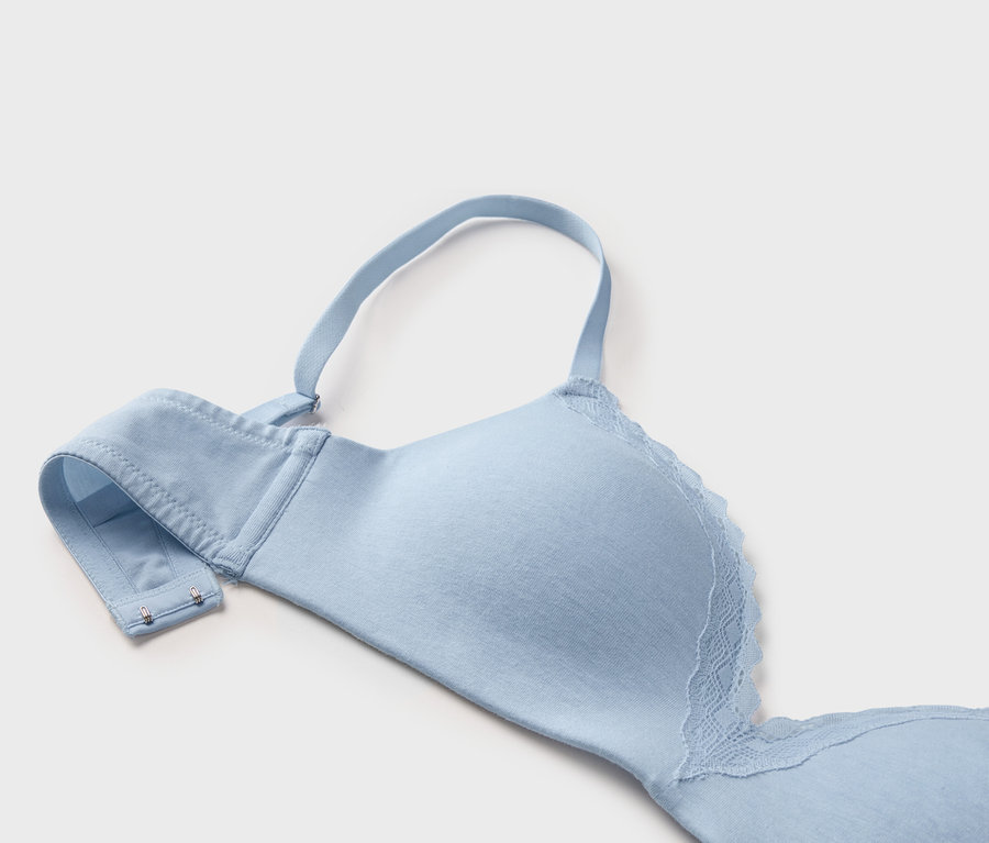 Gros plan d'un soutien-gorge bleu clair avec de la dentelle et des bretelles réglables sur fond blanc.
