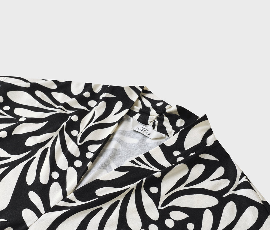 Gros plan d'une robe noire et blanche avec un motif de feuilles et une étiquette « MY STYLE ».
