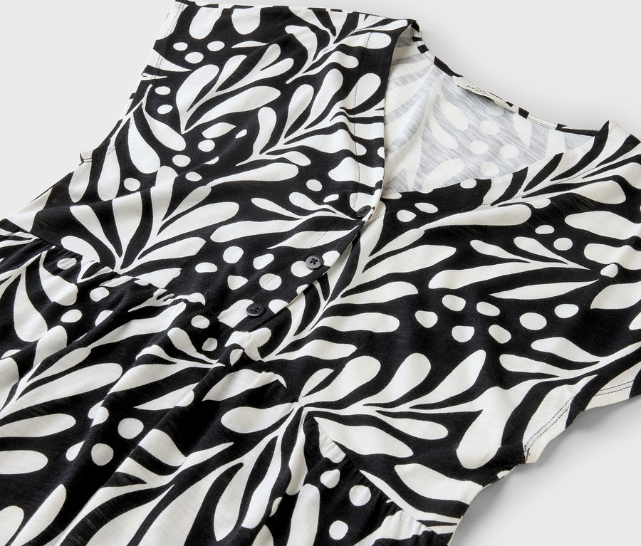Gros plan d'une robe noire et blanche à motifs de feuilles et à boutons.