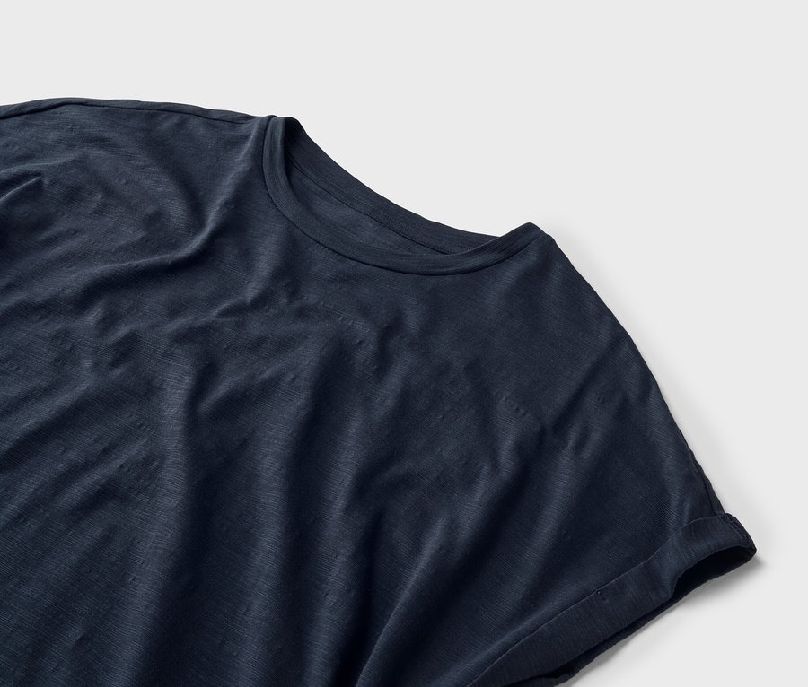Gros plan d'un t-shirt bleu marine sur un fond blanc.