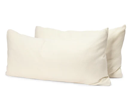 Deux oreillers rectangulaires de couleur crème sont posés l'un sur l'autre sur un fond blanc.