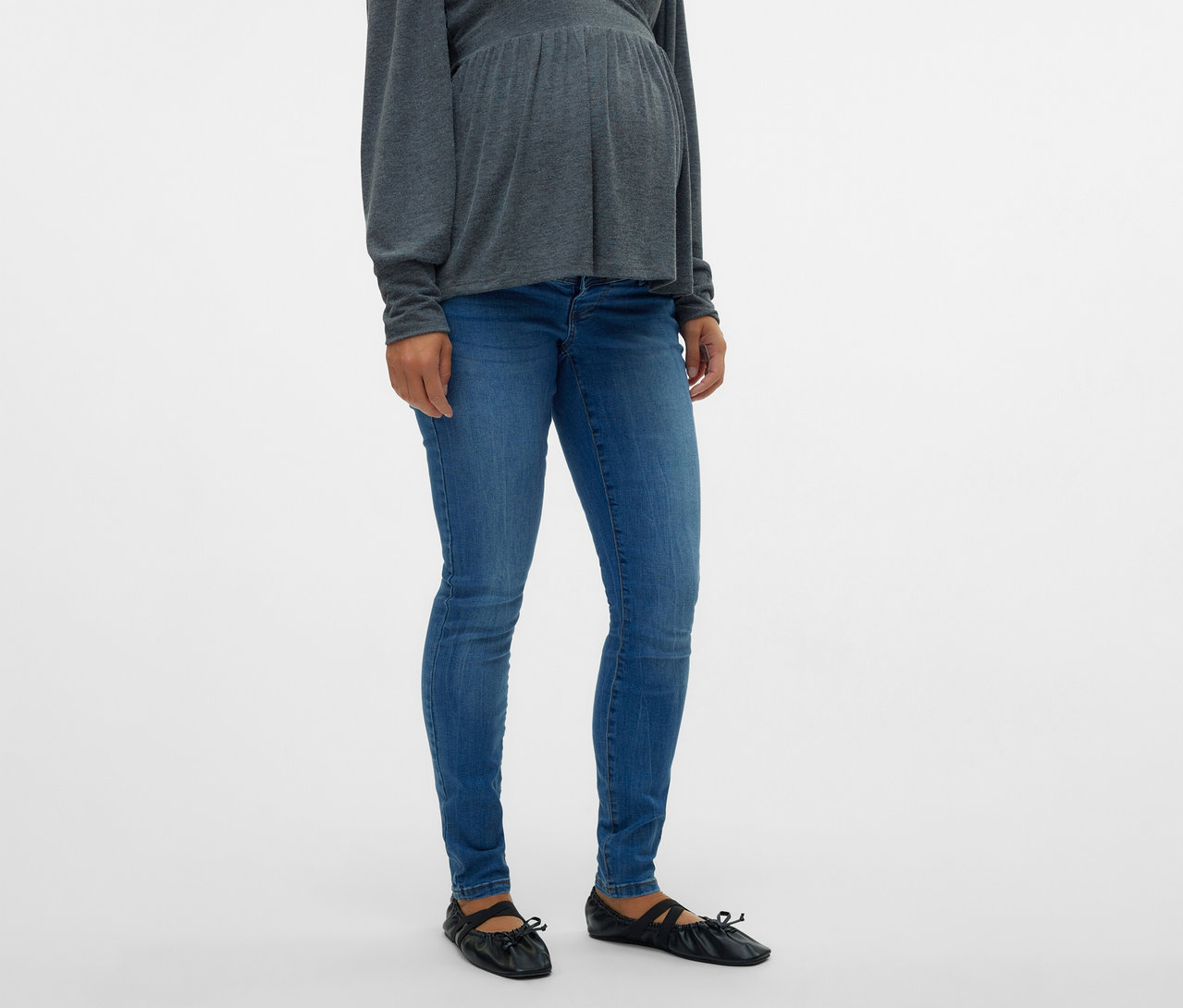 Femme enceinte portant un haut gris et un jean skinny MAMALICIOUS «
MLMILA » avec des ballerines noires.