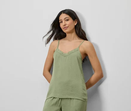 Femme portant un haut en satin vert avec de la dentelle et un short assorti.