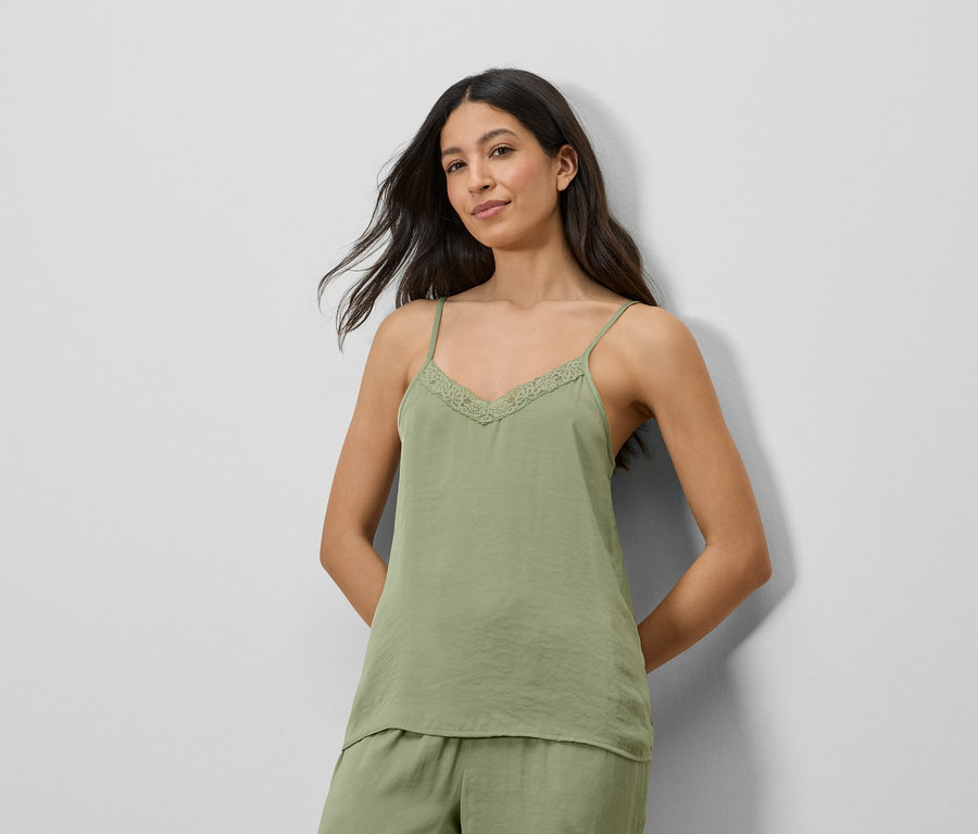 Femme portant un haut en satin vert avec de la dentelle et un short assorti.