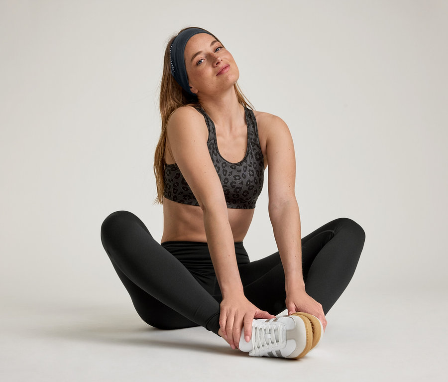 Femme assise, jambes écartées, portant des leggings de sport «
ActiveSoft
».