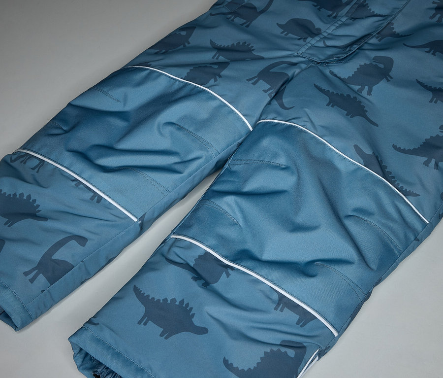 Gros plan sur un pantalon bleu avec motif dinosaure et accents blancs.