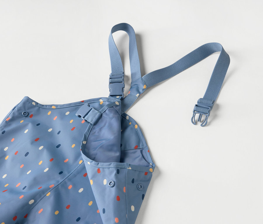 Tablier bleu pour enfant avec des points colorés et des bretelles bleues sur fond blanc.