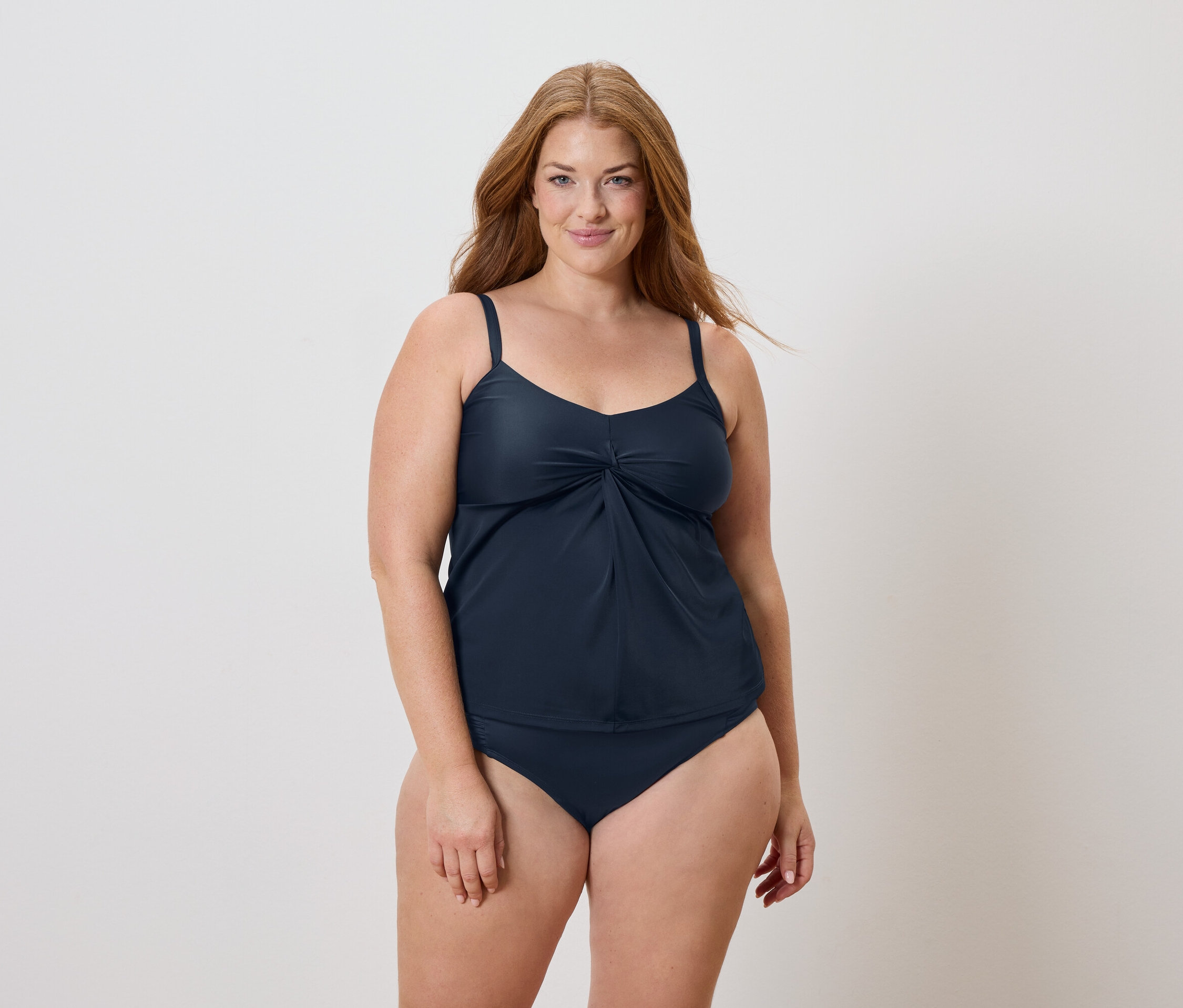 Femme aux longs cheveux roux portant un maillot de bain bleu marine.