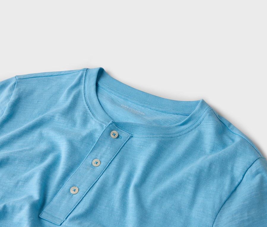 Gros plan d'un t-shirt Henley bleu clair avec trois boutons.