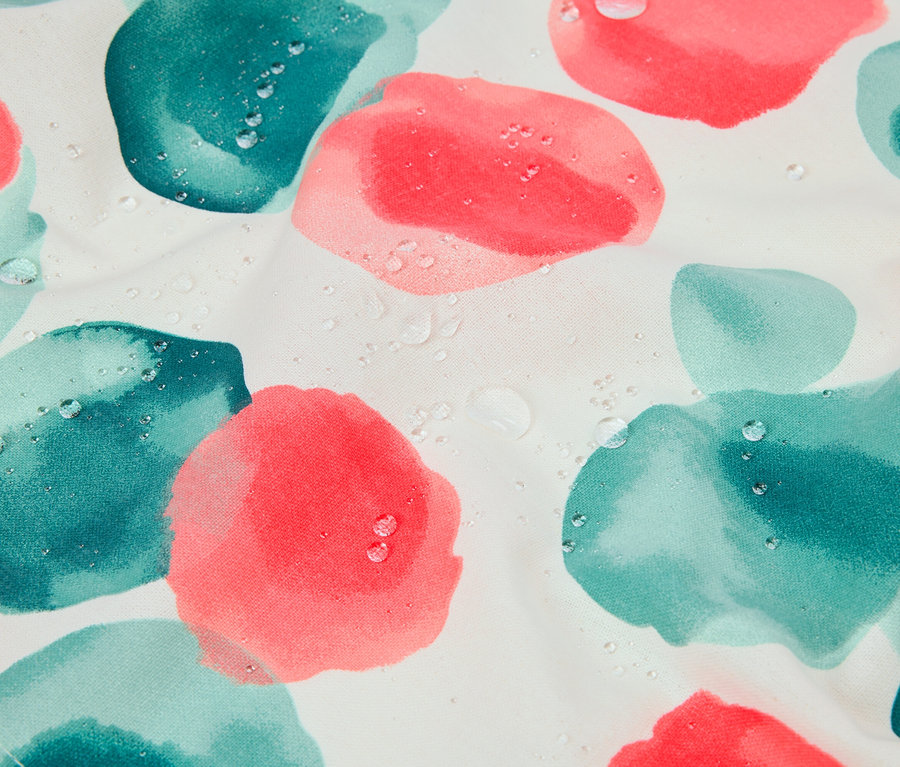 Gros plan sur un tissu à fleurs roses et turquoise avec des gouttes d'eau.