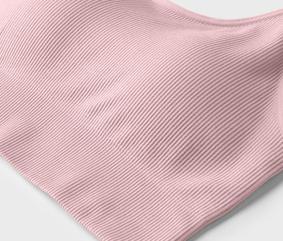 Gros plan d'un soutien-gorge de sport rose clair côtelé sur fond blanc.